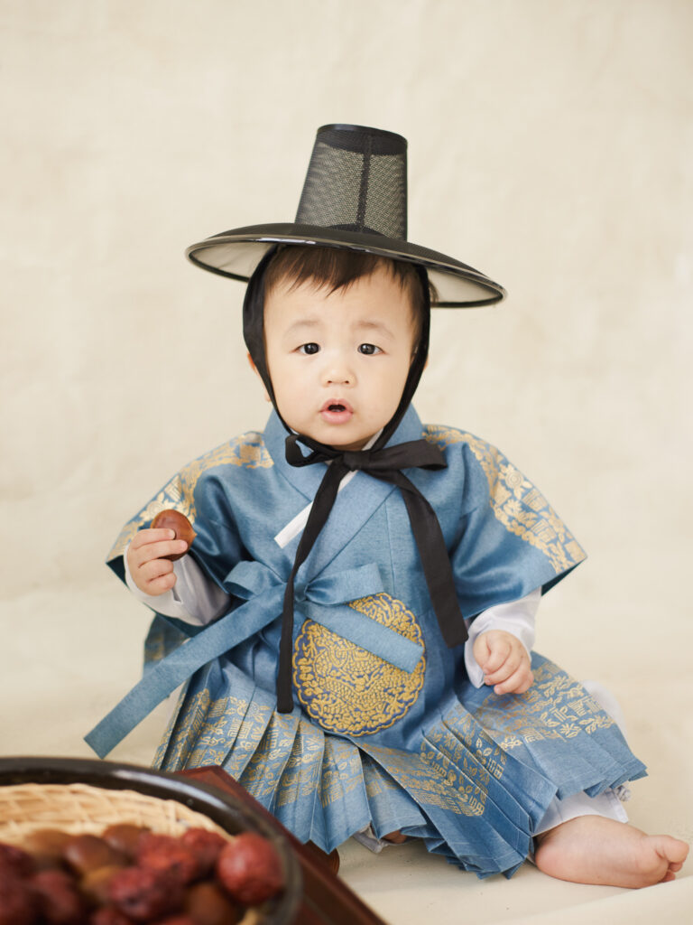 Chicago dol close up portrait of baby in blue hanbok with traditional hat looking toward the camera