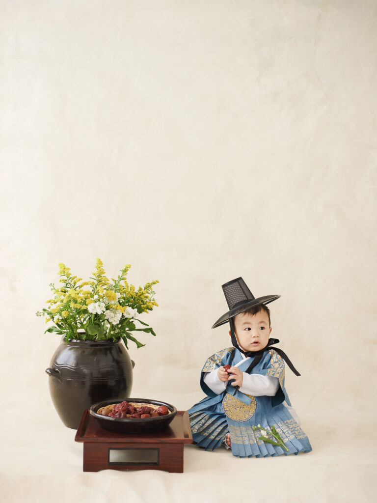 Chicago dol photography setup with traditional props, flowers, and child seated in hanbok on a neutral backdrop