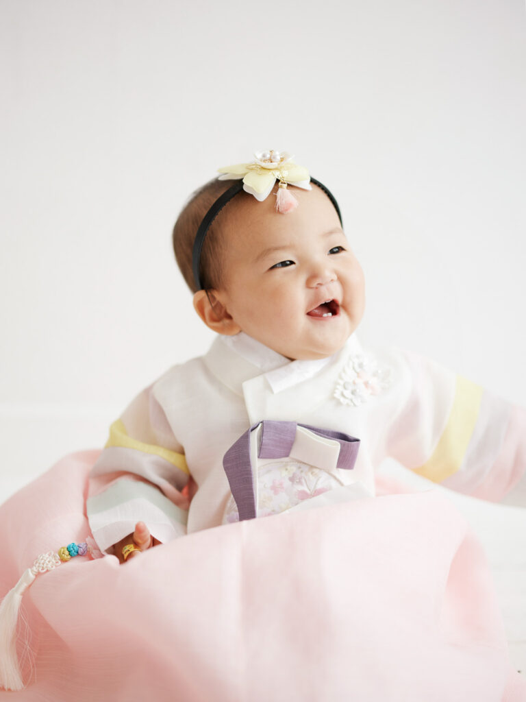 Chicago dol session close up of baby girl smiling in pastel hanbok with delicate details and soft natural light