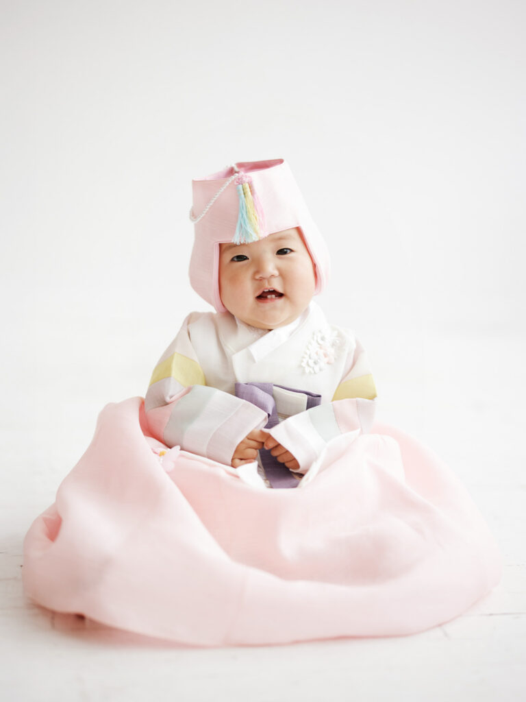 Chicago dol photography baby in soft pink hanbok seated on the floor with a gentle, light-filled studio backdrop