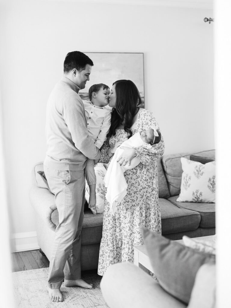 Black and white portrait of parents standing together holding newborn baby during in-home newborn session in Western Springs Illinois