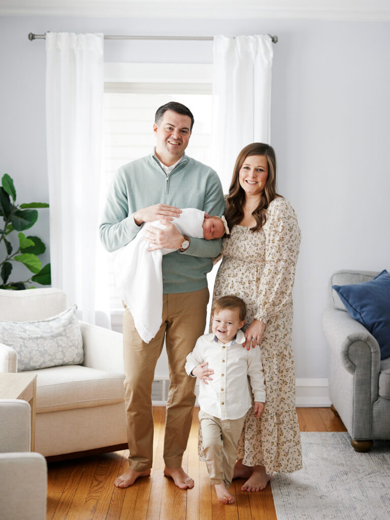 Parents standing with toddler sibling and newborn baby during in-home newborn session in Western Springs Illinois