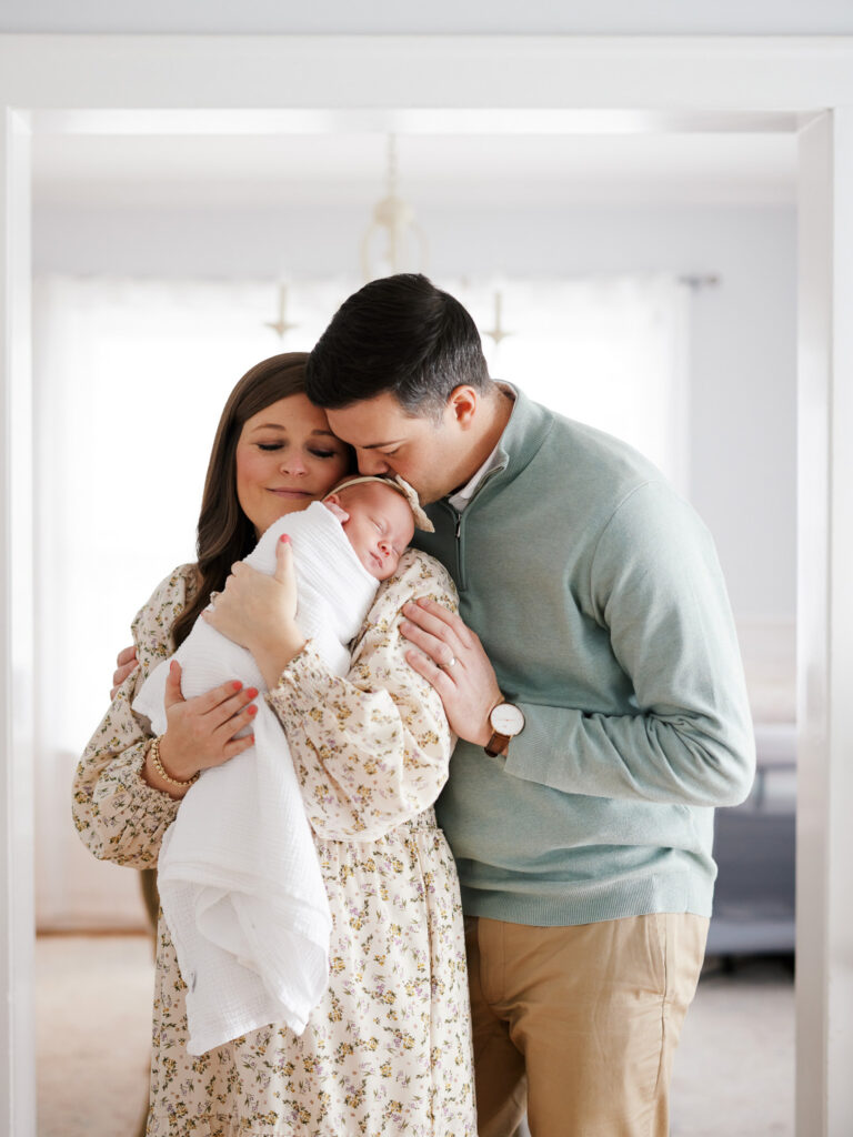 Mother and father holding newborn baby together cheek to cheek during in-home newborn session Western Springs IL