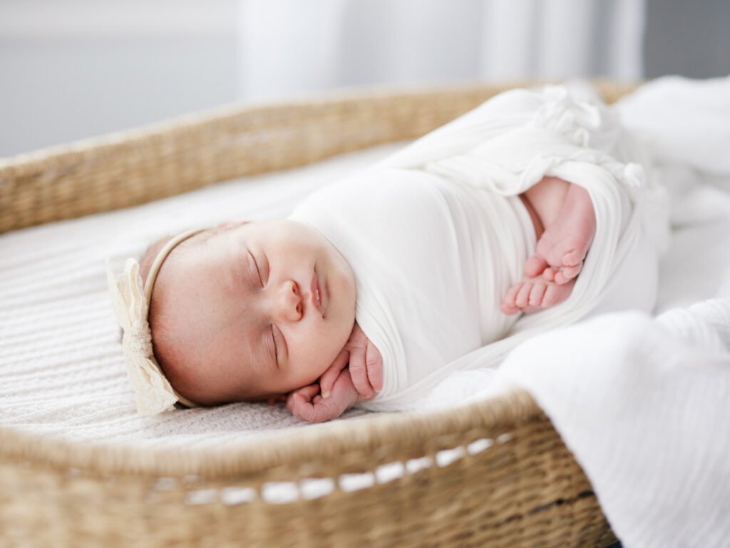 Sleeping newborn baby in white wicker Moses basket during in-home newborn session in Western Springs Illinois