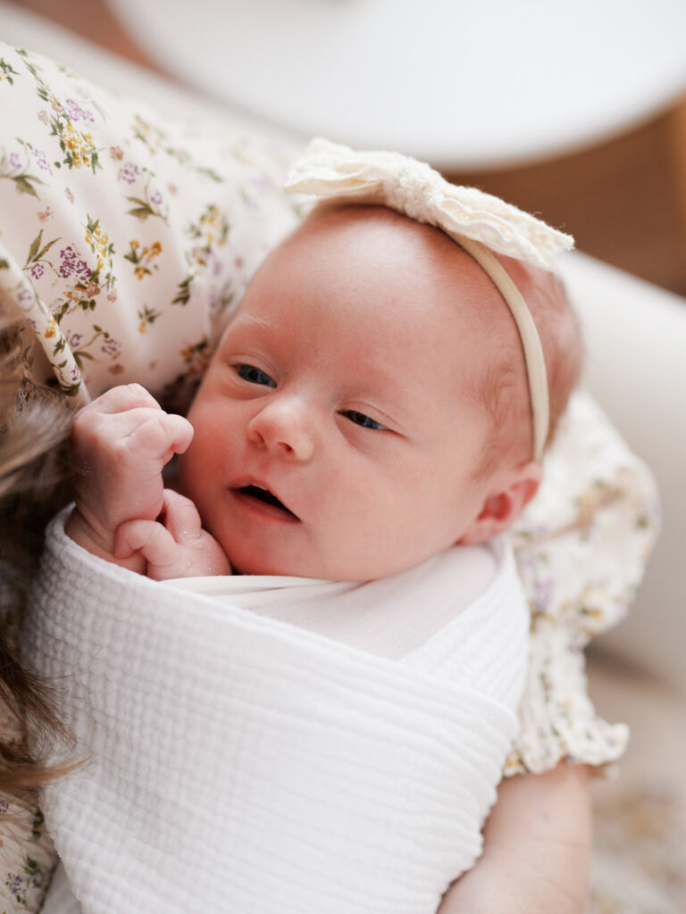 Close-up portrait of alert newborn baby girl with white headband, in-home newborn session Western Springs IL