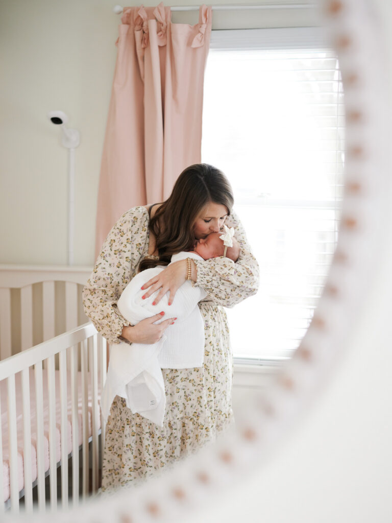 Mother holding newborn baby in blush nursery during in-home newborn photography session in Western Springs Illinois